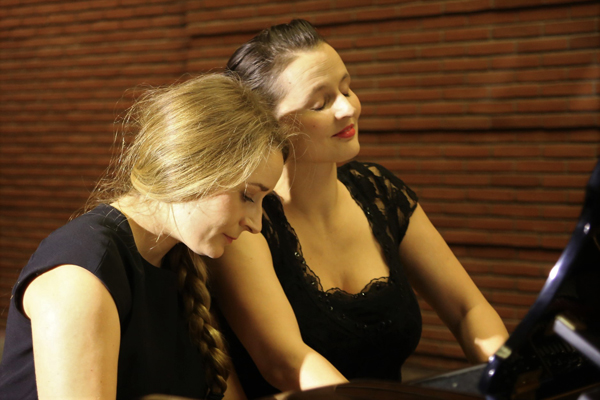 zwei Frauen, die gemeinsam an einem Klavier sitzen