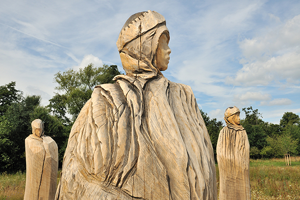 three large wooden figures in the countryside