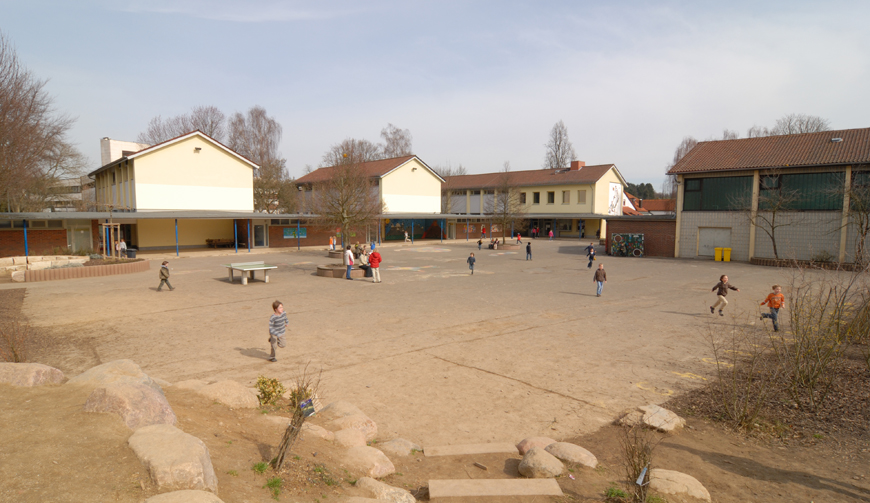 einen sehr großen Hof, in dem einige Kinder spielen; im Hintergrund stehen mehrere Häuser