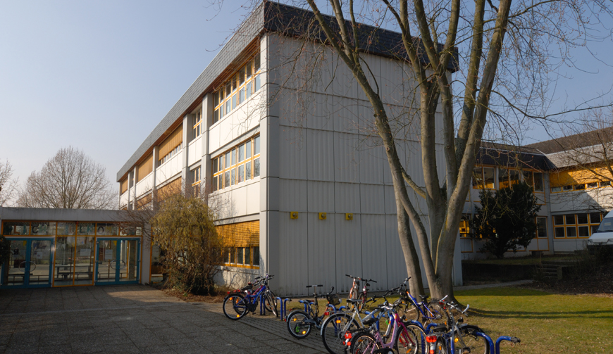 einige auf einem Hof an Fahrradständer angeschlossene Fahrräder vor einem großen Gebäude