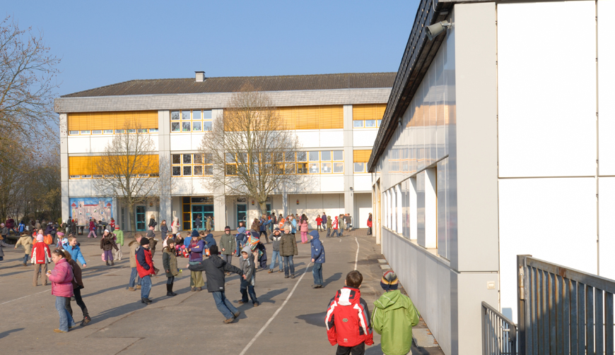 viele spielende Kinder in einem Innenhof vor einem großen Gebäude