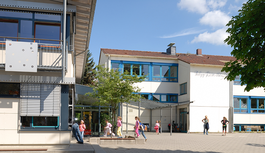 den Blick über einen Hof auf mehrere Gebäude, davor spielen Kinder