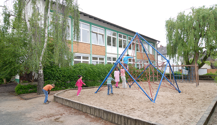 ein Klettergerüst in einem Sandkasten, an dem Kinder spielen