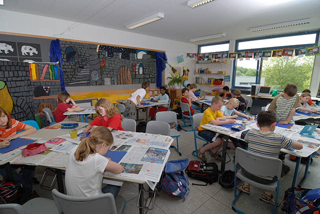 Blick in eine Schulklasse, in der Kinder an den Tischen sitzen und arbeiten