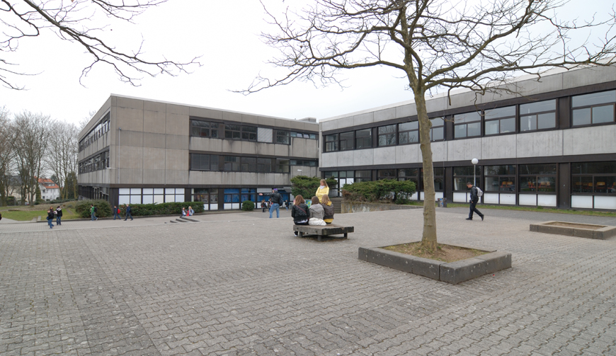 den Blick auf einen großen Hof mit einem großen grauen Gebäude im Hintergrund
