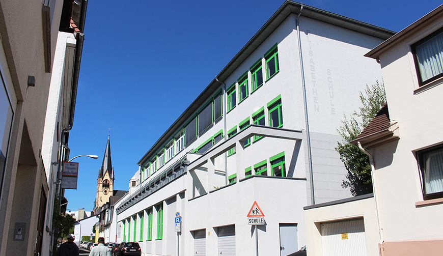 den Blick durch eine Straße auf ein großes weißes Gebäude mit grünen Fensterrahmen