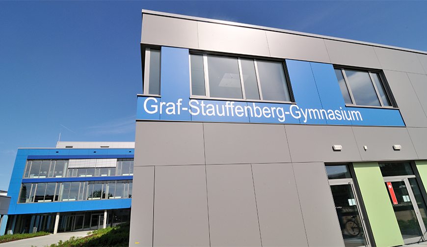 Blick auf ein grau-blau gestrichenes Gebäude mit dem Schriftzug Graf-Stauffenberg-Gymnasium