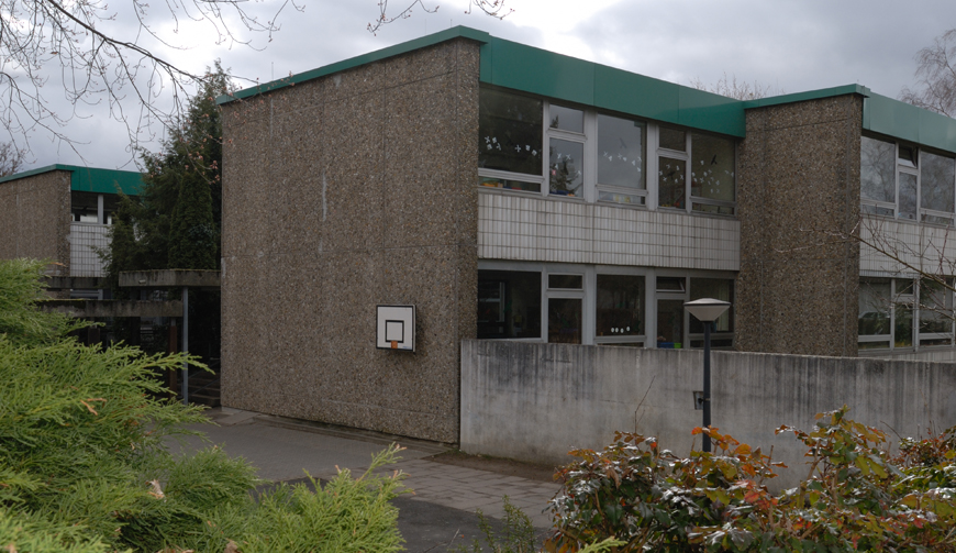 ein großes graues Gebäude, an dessen Seite ein Basketballkorb angebracht ist