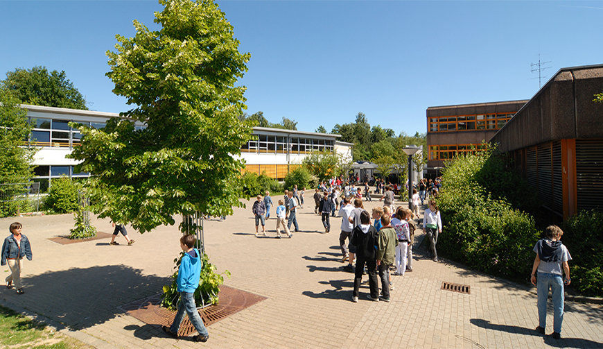 einen großen Hof mit einem Baum in der Mitte, auf dem sich viele junge Leute befinden