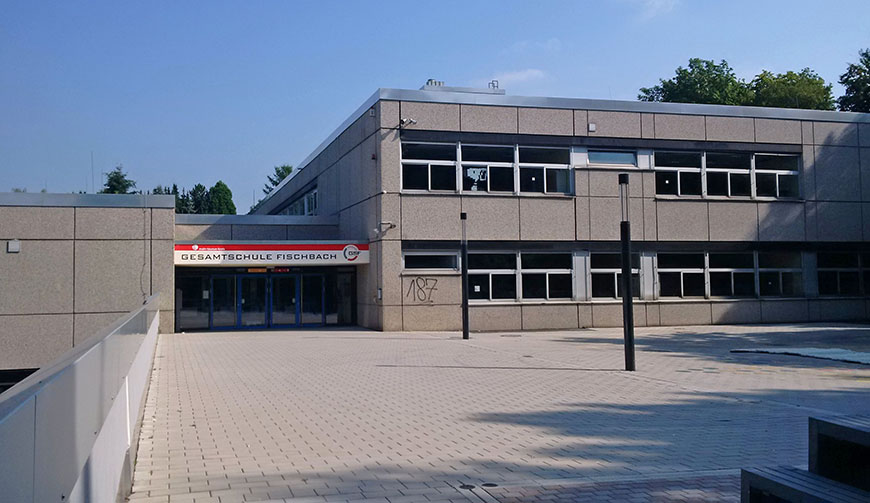 Blick über einen Hof auf ein graues Gebäude