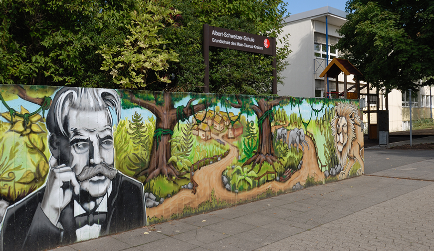 eine bunt bemalte Mauer mit Bäumen und einem Gebäude im Hintergrund