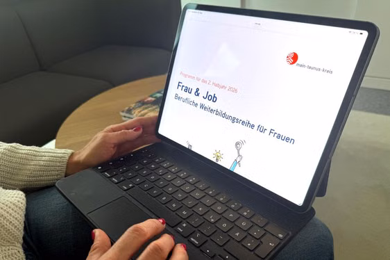 Eine Frau schaut sich das Frau & Job Programm auf dem Table an