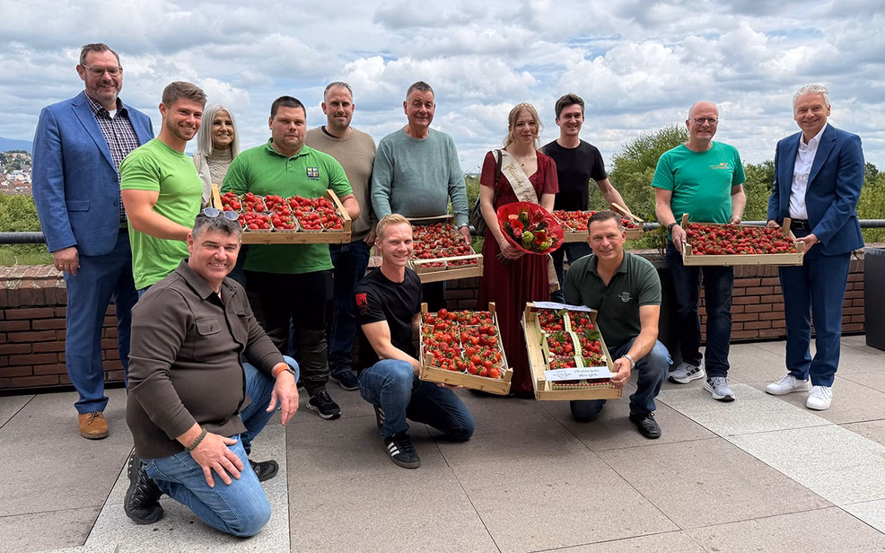 Ein Gruppenfoto mit mehreren Menschen, die Erdbeerschalen in den Händen halten
