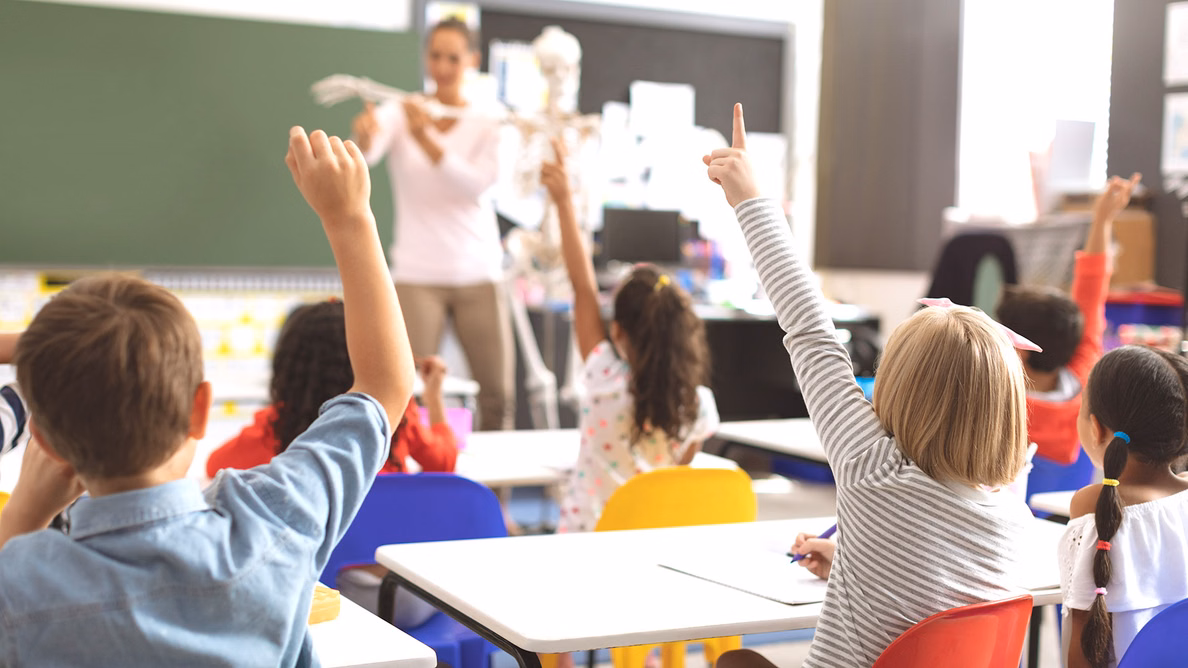 Kinder im Klassenraum, die sich engagiert melden