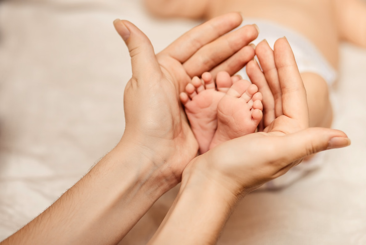 Eine Erwachsene Hand hält zwei Babyfüße