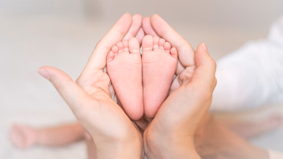 Zwei Babyfüße, die von Händen gehalten werden