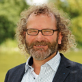 Portrait eines Mannes mit Brille und Bart, aufgenommen im Grünen