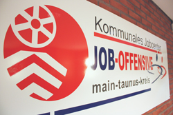 Ein Schild an einer Wand, auf dem zu lesen ist: Kommunales Jobcenter, Job-Offensive, Main-Taunus-Kreis
