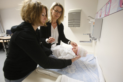 zwei Frauen, die ein Baby auf einen Wickeltisch legen