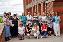 eine Gruppe von rund 15 Frauen auf einem Balkon, einige von ihnen halten eine Plakette in Form des Schriftzugs KiSS in den Händen
