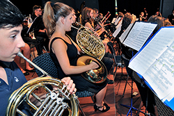 Jugendlich in einem Orchester mit unterschiedlichen Instrumenten und Notenblättern