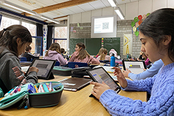 einen Klassenraum voller Schüler, die digital auf Tablets arbeitet