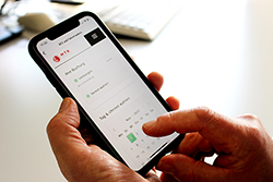 Hände halten ein Handy, auf dem Display ist die Terminbuchung auf der Main-Taunus-Kreis Website dargestellt