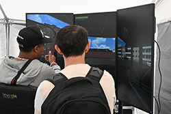 zwei junge Männer sind von hinten zu sehen und sitzen vor einem Fahrsimulator