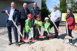 Ein Foto eines symbolischen Spatenstichs, bei dem  alle Beteiligten wie Landrat Michael Cyriax, Kreisbeigeordneter Axel Fink, Bürgermeister Klaus Schindling eine Schaufel in der Hand halten und Sand schaufeln.