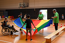 Menschen mit einem bunten Schwungtuch in einer Sporthalle