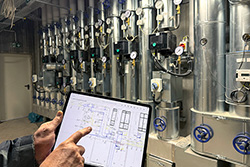 Tablet mit geoeffnetem Plan des Hallenbads vor der Lueftungsanlage im Inneren des Schwimmbads