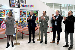 Vier Personen stehen im Foyer einer Schule und klatschen in die Hände 