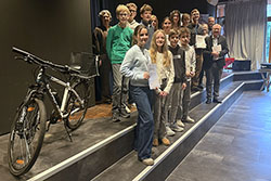 Gruppenfoto mit mehreren Kindern und vier Erwachsenen; neben ihnen steht ein Fahrrad