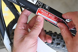 Eine Person bringt einen roten Sicherheitsaufkleber mit der Aufschrift „Finger weg! Mein Rad ist codiert“ an einem Fahrrad an