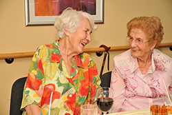 zwei Altenheimbewohnerinnen lachend im Gespräch.