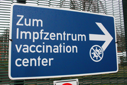 ein blaues Schild mit einem Pfeil und dem Text Zum Impfzentrum