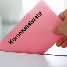 Wahlschein wird in eine Urne eingeworfen