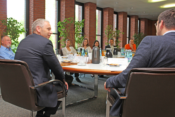 eine Gruppe Männer und Frauen, die um einen großen Konferenztisch sitzen.