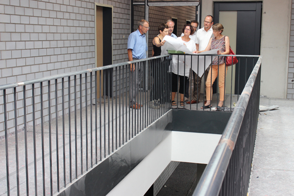ein im Bau befindliches Treppenhaus, in dem einige Personen stehen und in Pläne schauen