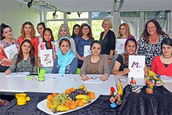 eine Gruppe Frauen, die sich um einen großen Tische versammelt haben, auf dem Obst steht