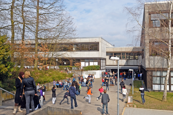 die Ansicht über einen Hof, in dem sich Schüler bewegen, auf ein Schulgebäude