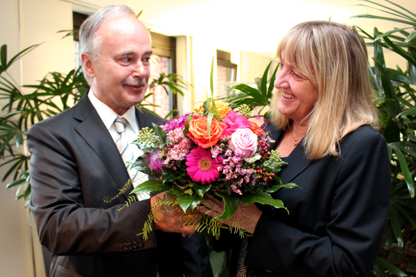 einen Mann im Anzug, der einer Frau einen Blumenstrauß überreicht