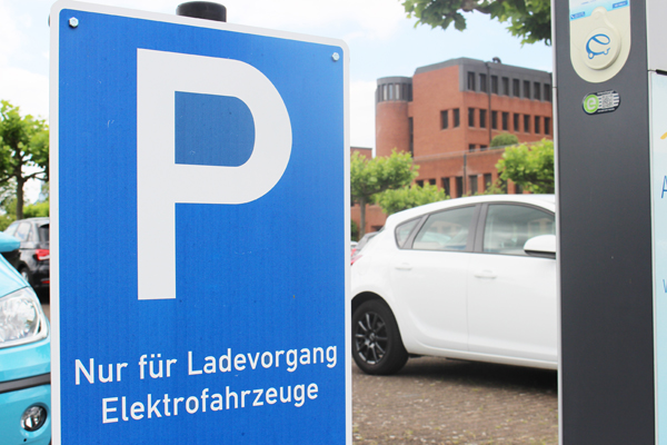 ein Parkplatz-Schild für Elektrofahrzeuge neben einer Ladesäule