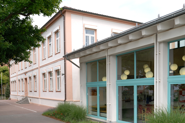 ein zweistöckiges Gebäude mit einem verglasten Anbau