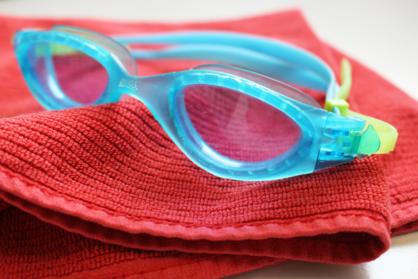 Blaue Schwimmbrille auf rotem Handtuch