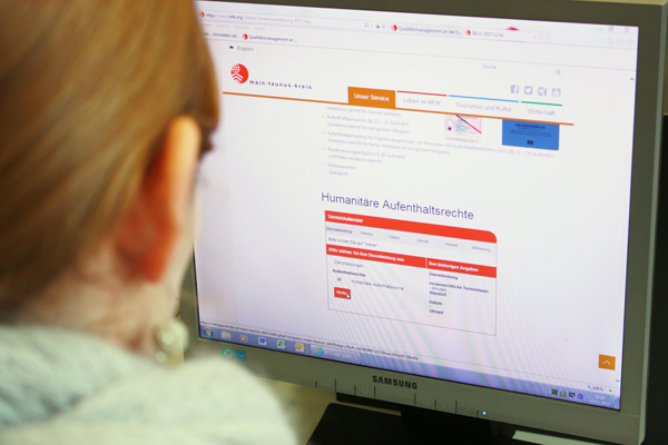 einen Computer-Bildschirm, auf dem die Internetseite des Main-Taunus-Kreises zu sehen ist und vor dem eine Frau sitzt