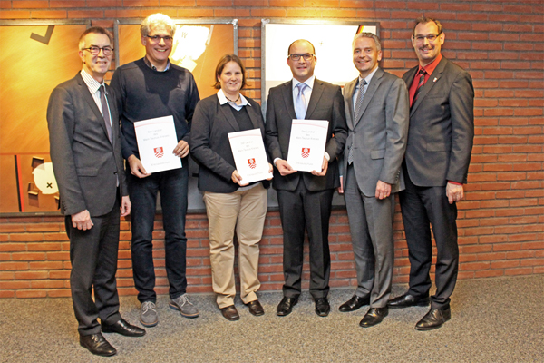 eine Gruppe von einer Dame und fünf Herren, drei von ihnen mit Urkunden in der Hand.