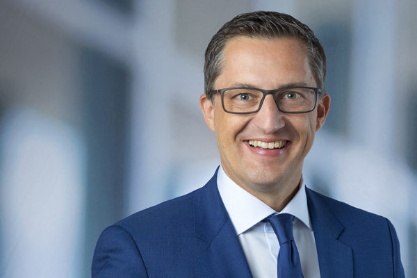 Portrait eines Mannes im blauen Anzug mit blauer Krawatte und Brille