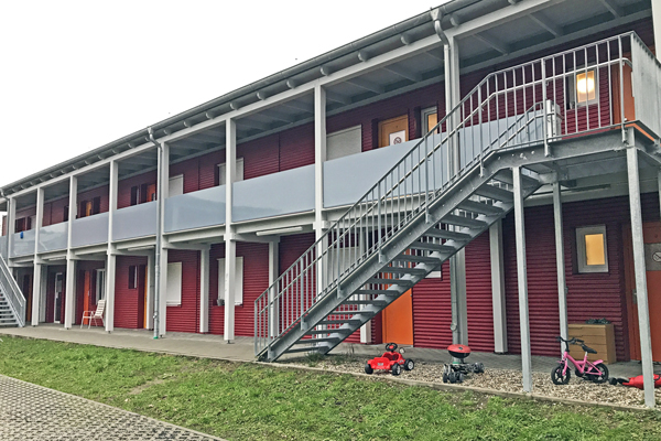 ein zweistöckiges, rotes Gebäude mit einem flachen Dach und einer Außentreppe