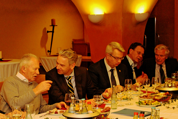 fünf Männer an einem Tisch mit Getränken und Essen, die in Gespräche vertieft sind